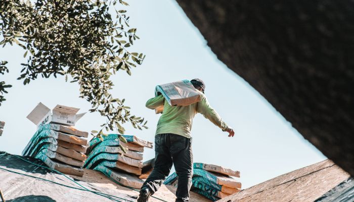man carrying shingles on a roof